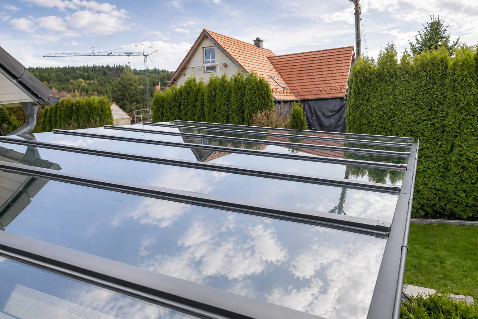 Glasüberdachung über Terrasse mit spiegelndem Glasdach und Metallprofilen